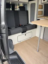 Budget zit/slaapbank in gekeurde opstelling, met gordels, in een camperinterieur