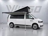 Witte VIGGO #2 camper met volledig uitgeklapte Fiamma luifel en beide steunpoten op de grijze studiovloer