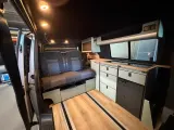 Camperinterieur met zit/slaapbank, keuken en zichtbare vloerrails
